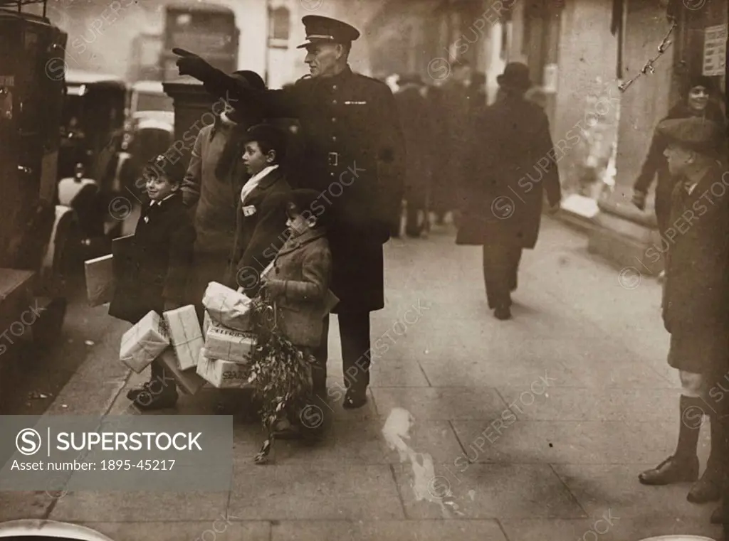 Small boys carrying mistletoe and parcels marked Selfridges’ are directed home by the commissionaire after a busy day shopping.