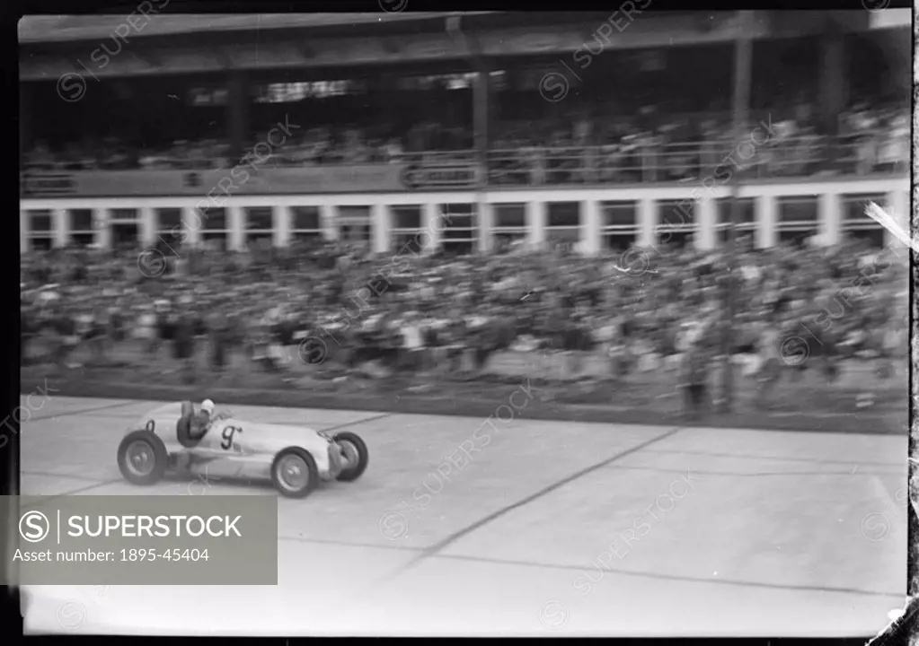 Photograph by Zoltan Glass. Spectators watch Fagioli, in car No 9, driving along the front of the pits.