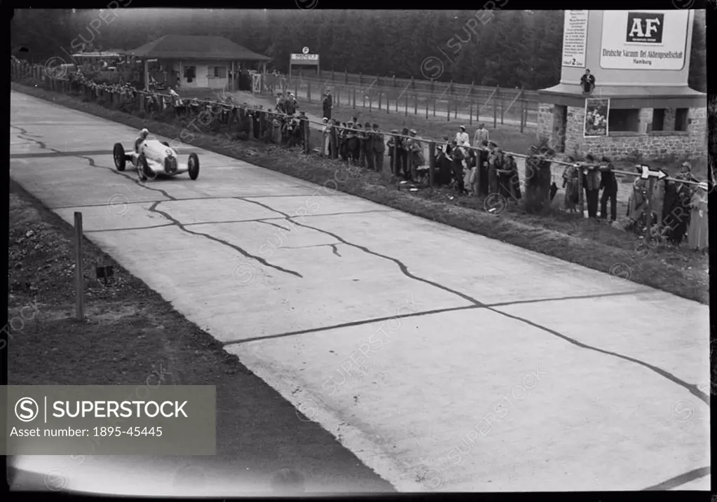 Photograph by Zoltan Glass. Spectators beside the race track watch car No 9, Luigi Fagiolis Mercedes-Benz W25 GP, driving past the back of the pits.
