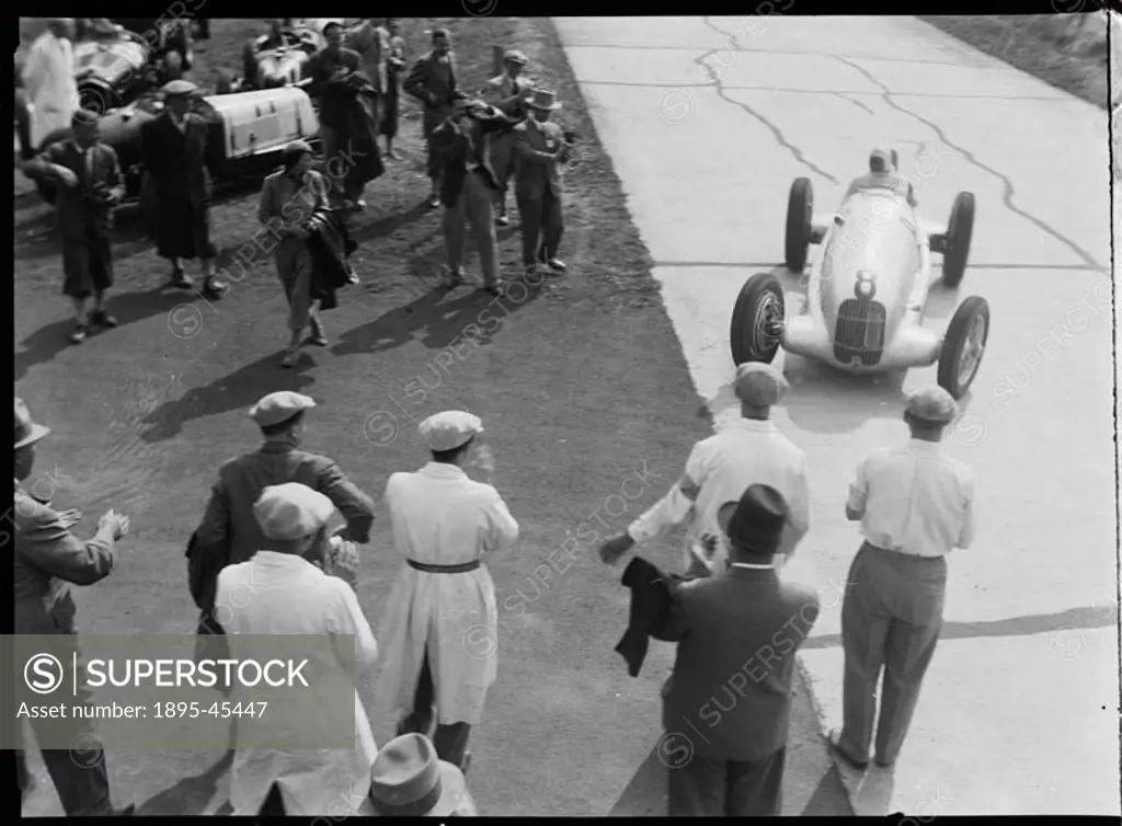 Photograph by Zoltan Glass. Mechanics and race-goers at the side of the race track greet car No 8, a Mercedes-Benz W25 GP, Hans Geier at wheel.