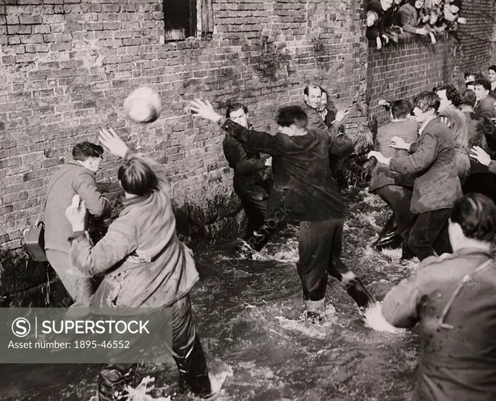 Gelatin silver print  A photograph of players fighting for possession of the ball in Henmore Brook during Shrovetide football in the village of Ashbou...