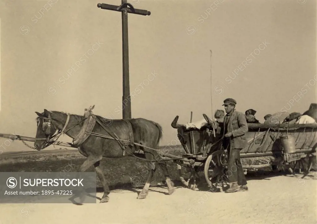 Russian refugees on a cart, Second World War, 1940s Russian civilians displaced by the War travel by horse and cart  They are passing a cross with a s...