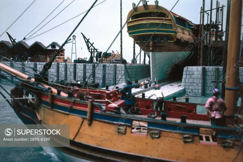 This view shows, in the foreground, a port bow view of a model of an English ketch-rigged sloop. In the background is a model of a 60-gun ship on the ...