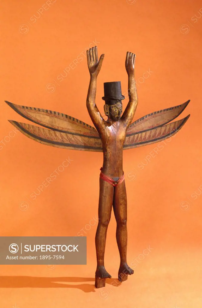 A Kareau figure of carved and painted wood, anthropomorphic, representing a standing male with wings and top hat, from the Nicobar Islands, Bay of Ben...