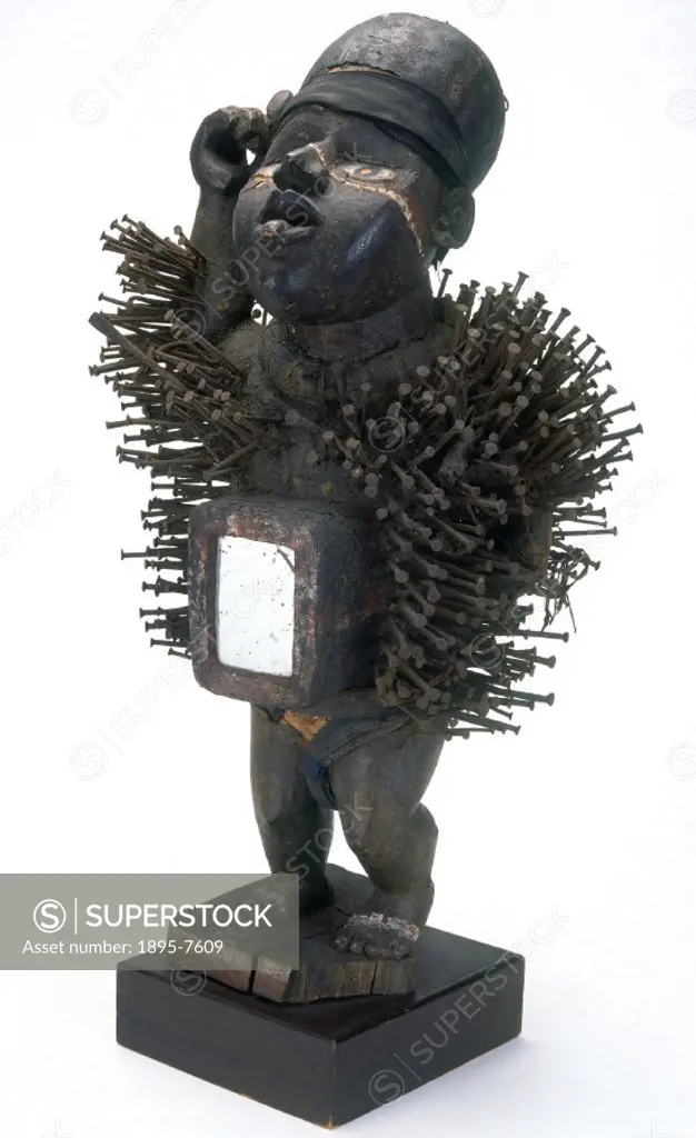 This fetish figure was probably made by the Bakongo tribe. It is a carved wooden male figure, with the body covered in nails, and a mirror on the fron...