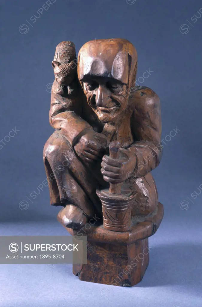Wooden carving of a witch with a cat and a pestle and mortar.