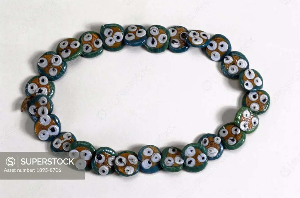 This necklace consists of 25 glass discs threaded on a string, each with inlaid circles of glass resembling eyes. It was used for protection against t...