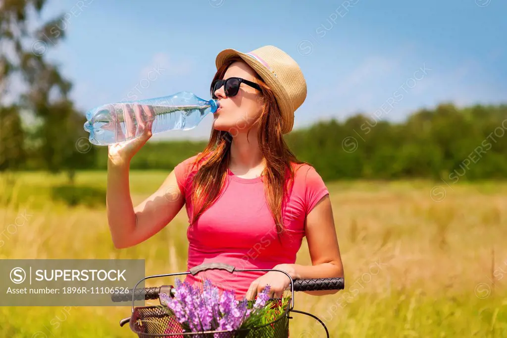 Active woman with bike drinking cold water, Debica, Poland
