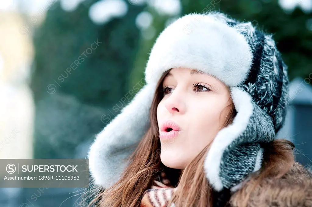 Young woman blowing into the cold air. Debica, Poland.