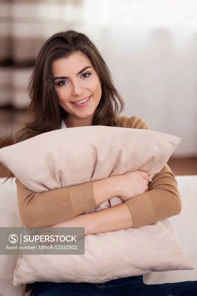 Portrait of beautiful woman embracing pillow on sofa. Debica, Poland