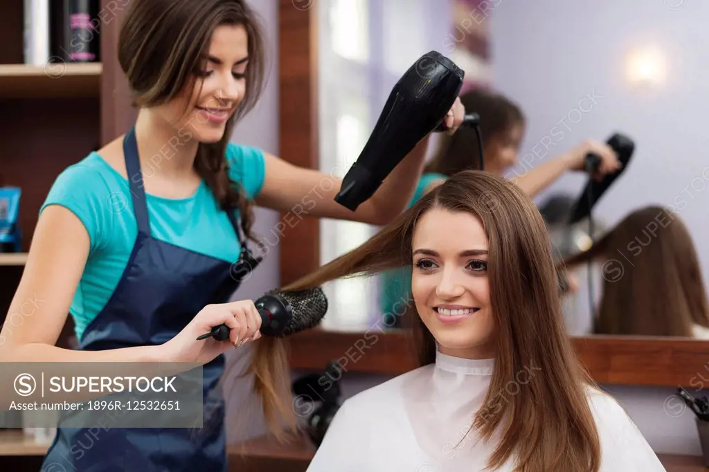 Female hairdresser using hairbrush and hair dryer. Debica, Poland