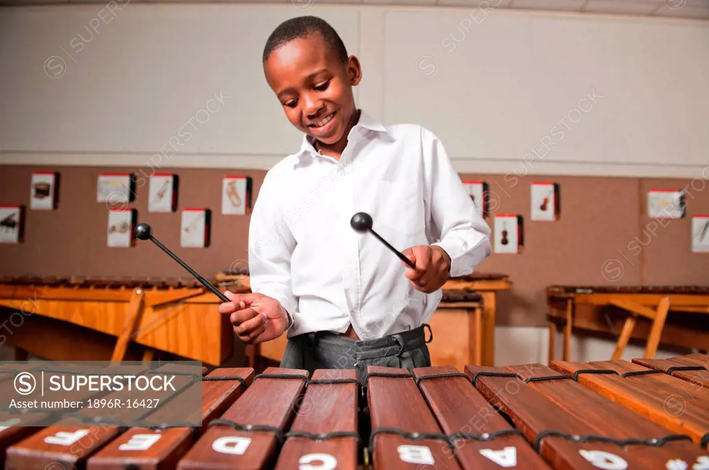 Boy playing wooden xylophone in classroom, Johannesburg, Gauteng Province, South Africa