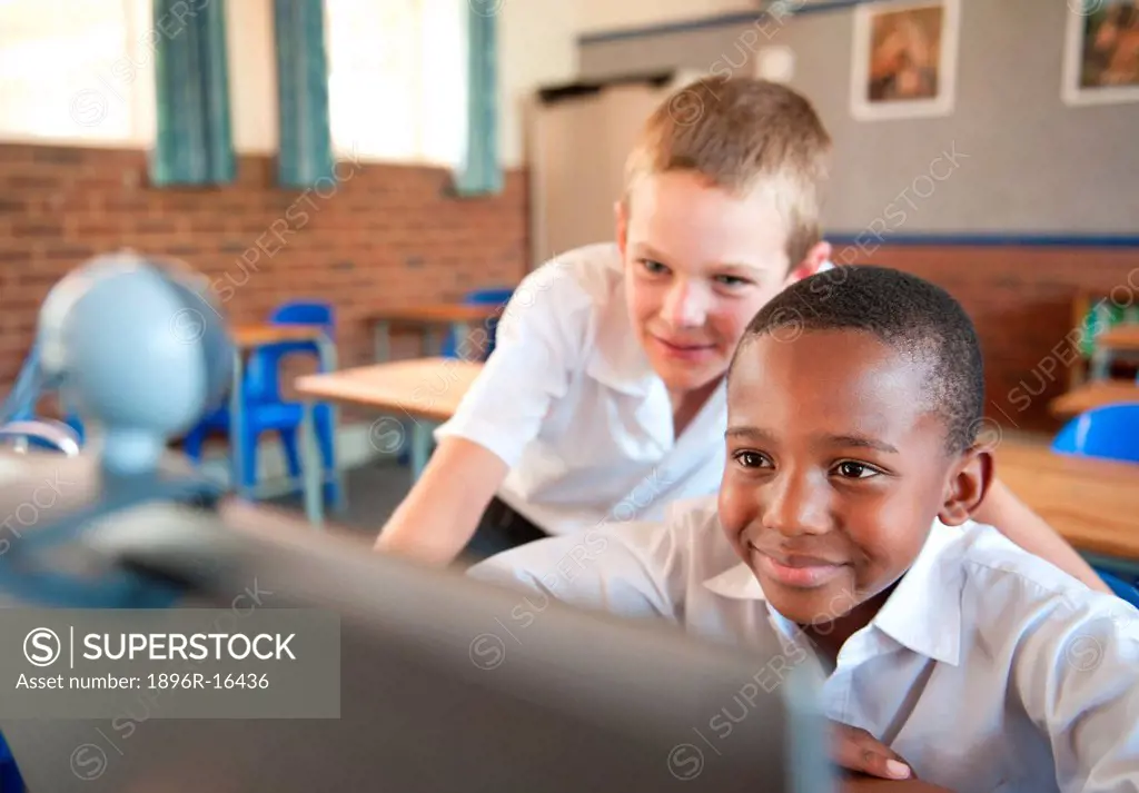 Two boys using laptop with web cam in classroom, Johannesburg, Gauteng Province, South Africa