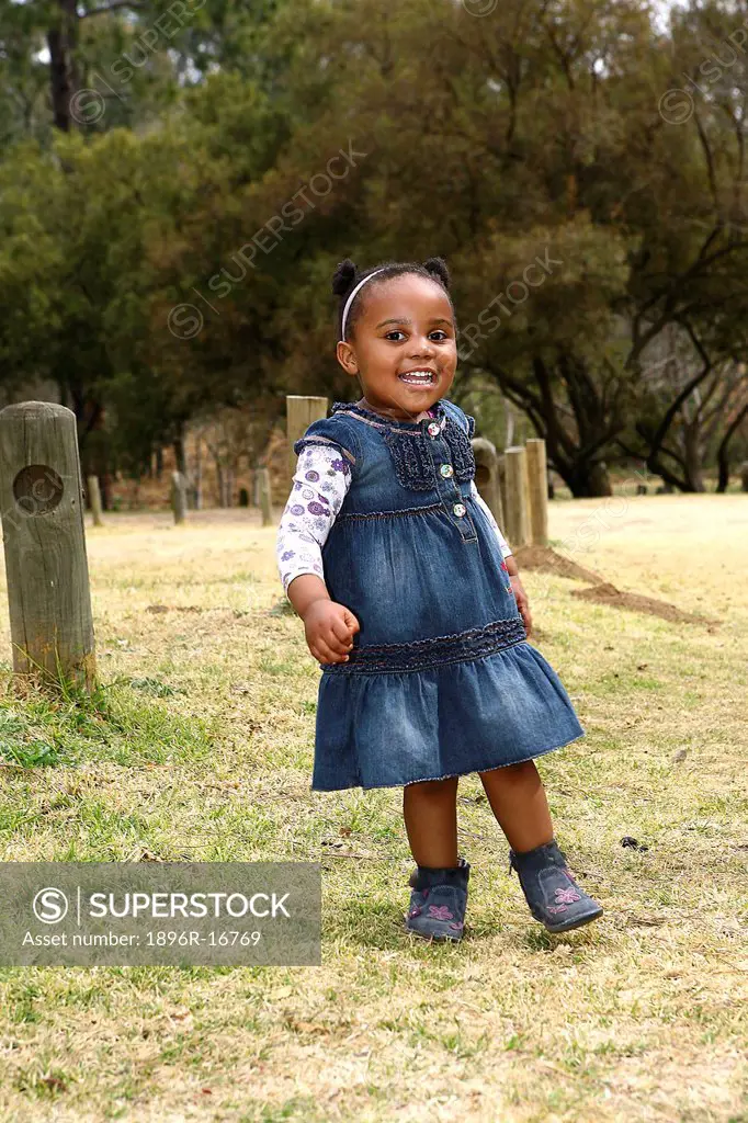Toddler girl standing facing camera and smiling broadly, Johannesburg, South Africa