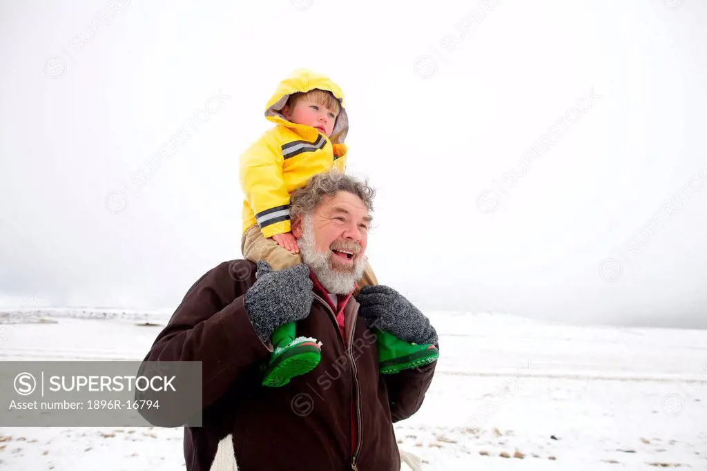 A portrait of a grandfather carrying his grandson on his shoulders through the snow, Kamberg, KwaZulu_Natal Province, South Africa