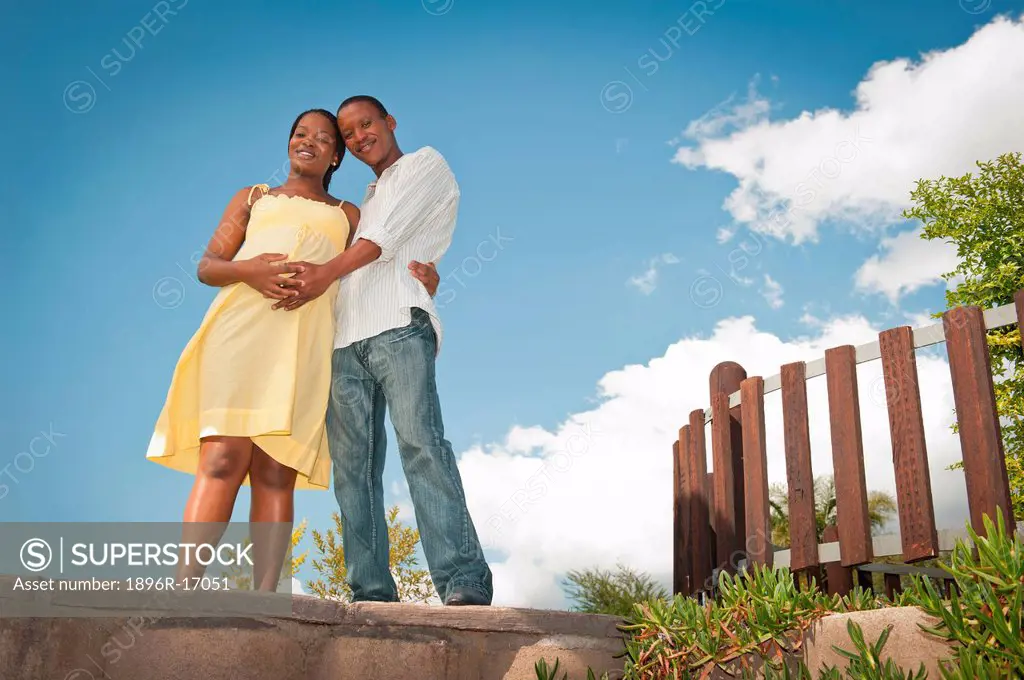 Pregnant woman and husband hugging outside, Johannesburg, Gauteng Province, South Africa