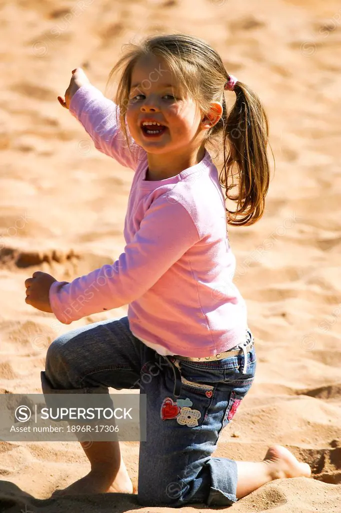 Portrait of toddler girl playing in sand and laughing, Johannesburg, South Africa