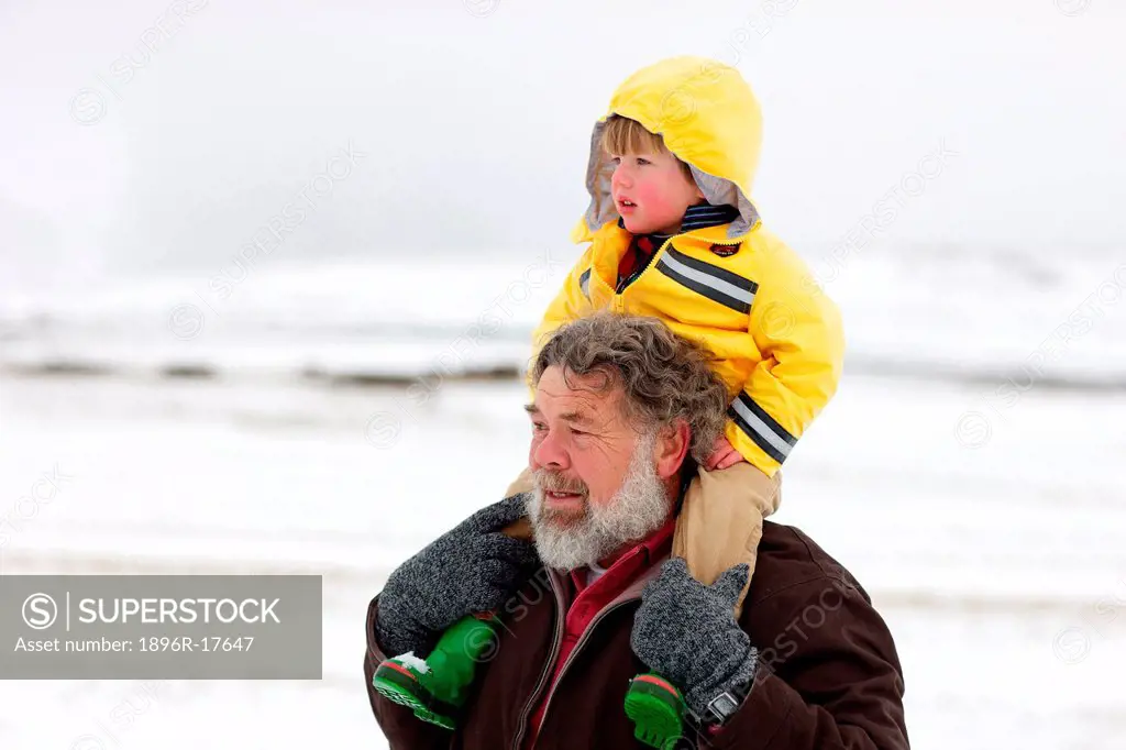 A portrait of a grandfather carrying his grandson on his sholders through the snow, Kamberg, KwaZulu_Natal, South Africa