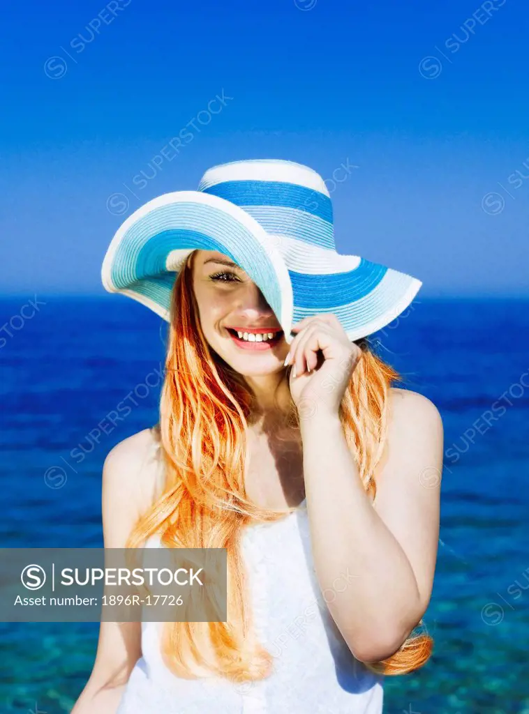 Woman wearing hat, smiling by sea, Antalya, Turkey