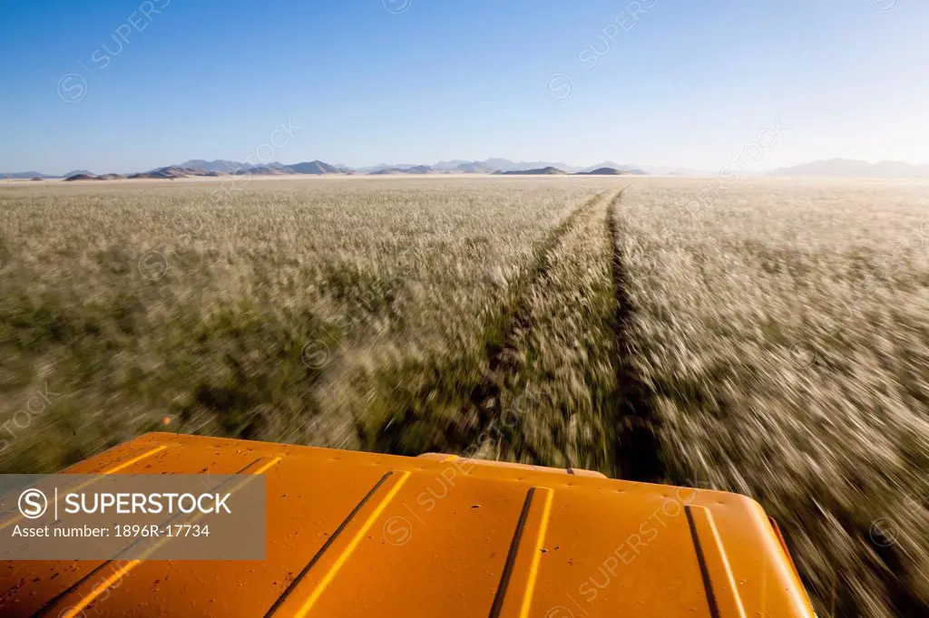 4x4 driving through endless expanse of Namibian grasslands, Namib Rand, Namibia