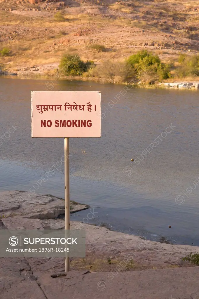 No smoking sign in both English and Hindi taken at the royal crematorium, Jaswant Thada, Jodhpur, Rajasthan, India. The image shows the sign, a lake a...