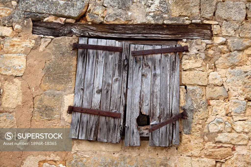 Old, sagging wooden shutters, rusted catches on window in Domme village, Dordogne, France