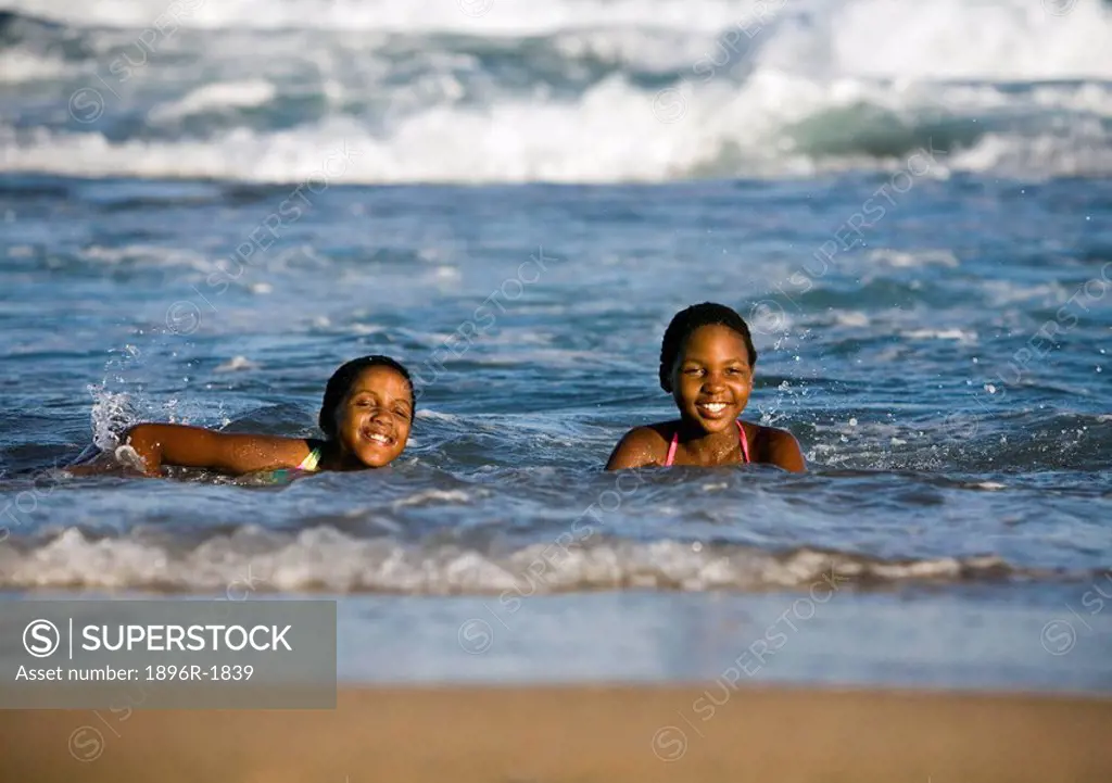 Two young girls play in the shallow waves, KwaZulu Natal Province, South Africa
