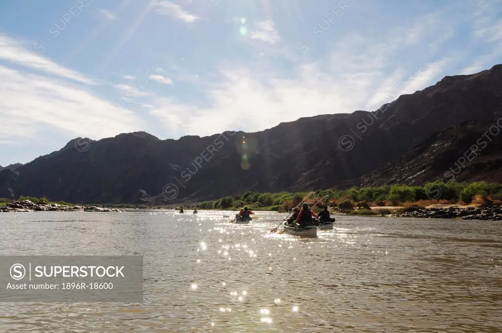 Canoeists paddling on river flowing below mountains, Orange River, Richtersveld National Park, Karas Region, Namibia