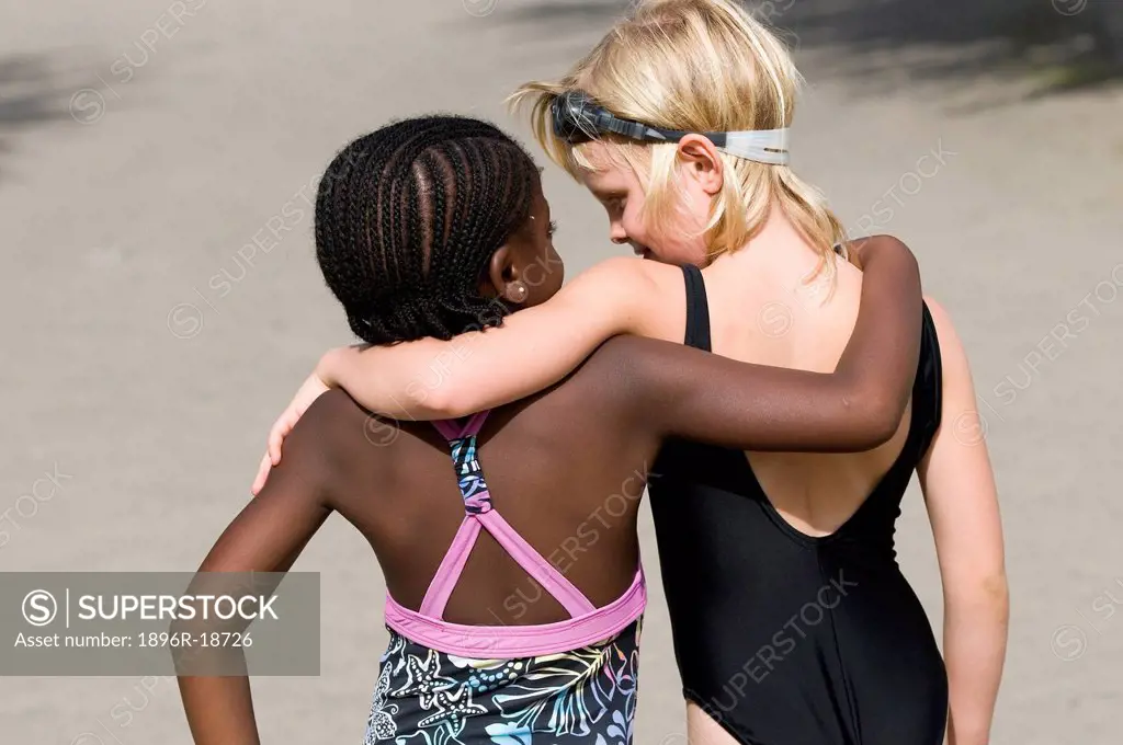 Rear view of two multi-racial girls hugging each other. Windhoek, Namibia.