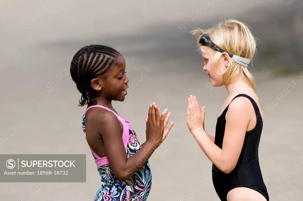 Two multi-racial girls playing a hand clapping game. Windhoek, Namibia.