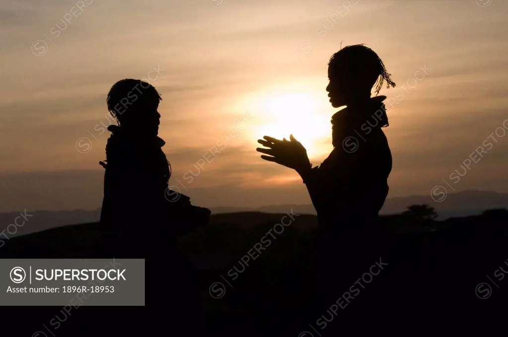 Silhouette of two Turkana girls talking together, Loigyalani, Northern Kenya.