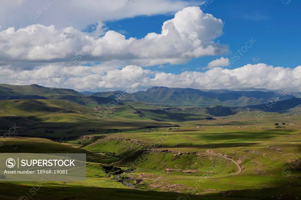 Telephoto view of a rural mountain road winding through green valleys. Southern Lesotho