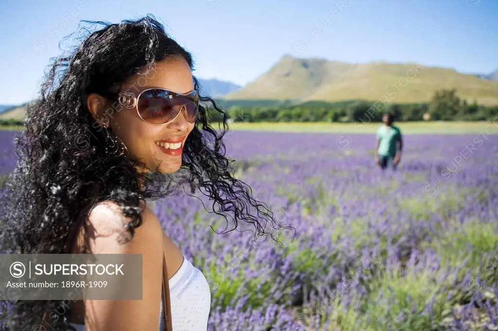 Close up view of woman standing in lavender field with man in background, Franschhoek, Western Cape Province, South Africa