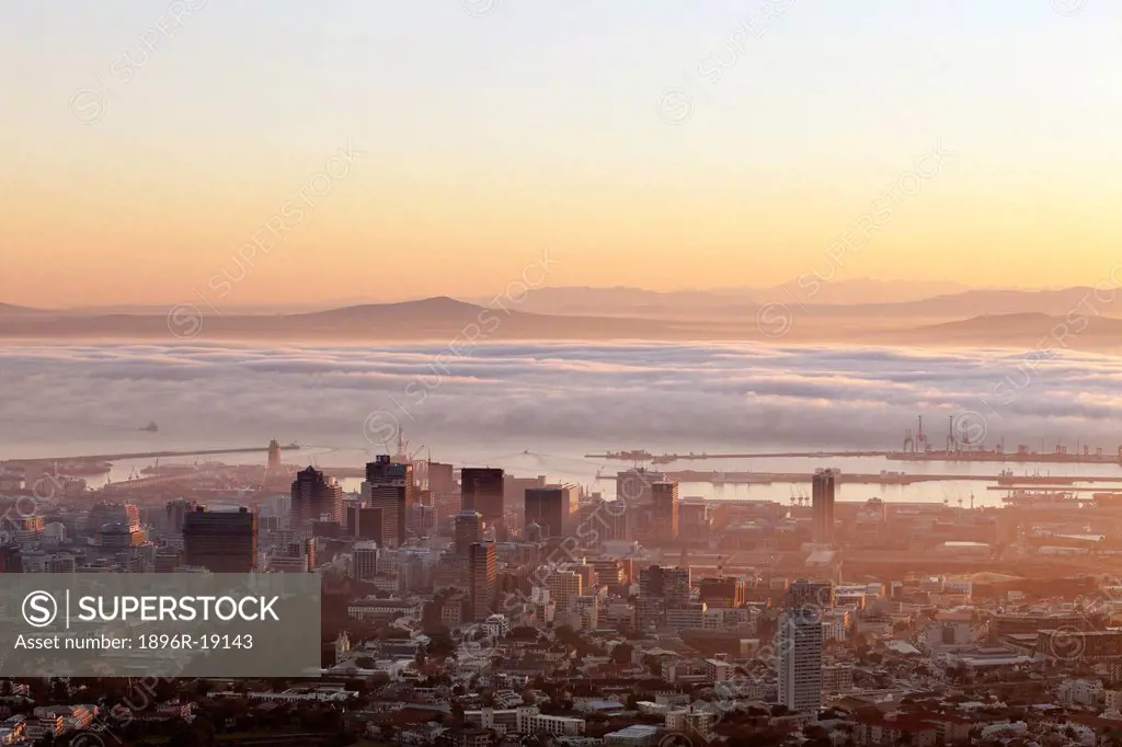 Telephoto view of dawn over the Cape Town CBD with mist in Table bay. Cape Town, Western Cape, South Africa.