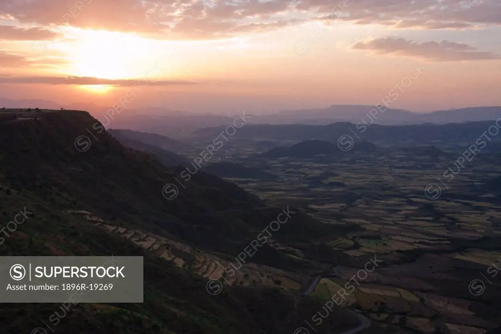 Sunset paints the sky over the patchwork of farmer's fields in the valley below Lalibela, Northern Ethiopia, famous for its rock-hewn churches.