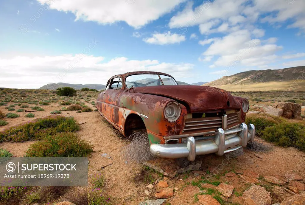 An old rusted car lies derelict amongst the fynbos, found in an open field in the Kamiesberg area near Springbok, South Africa
