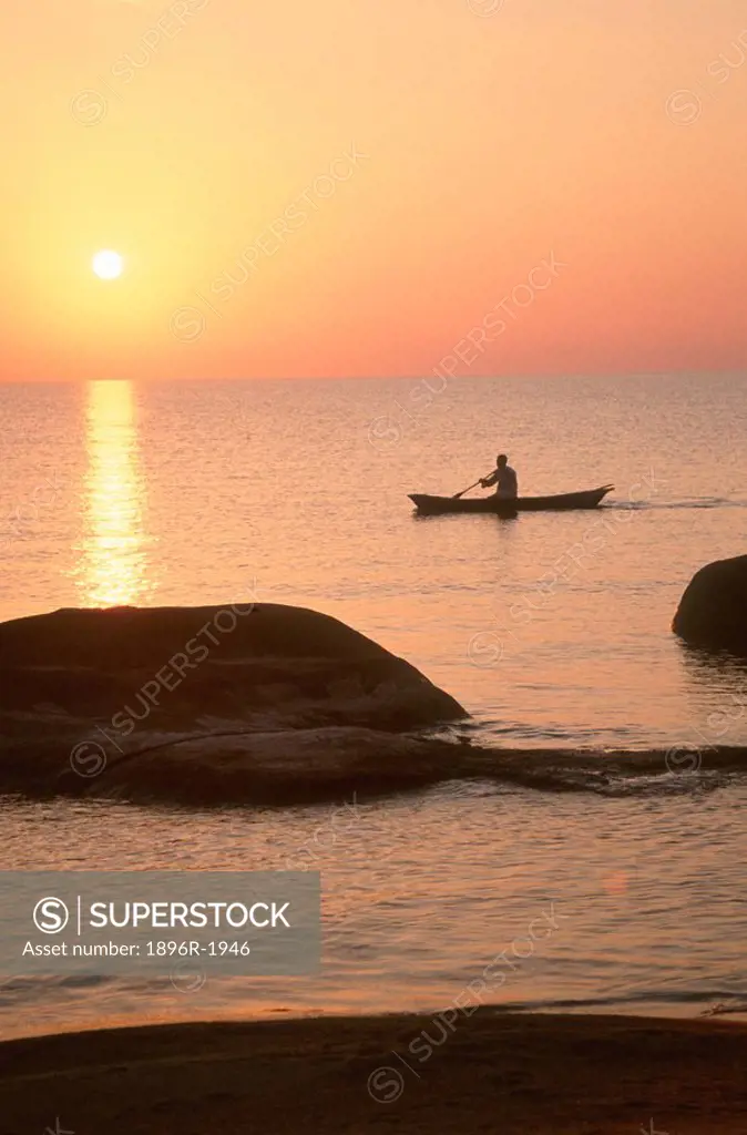 Silhouette of man in dug_out canoe against the setting sun, Senga Bay, Malawi