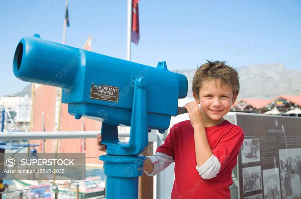 Boy standing next to telescope with Table Mountain in background, Cape Town, Western Cape Province, South Africa