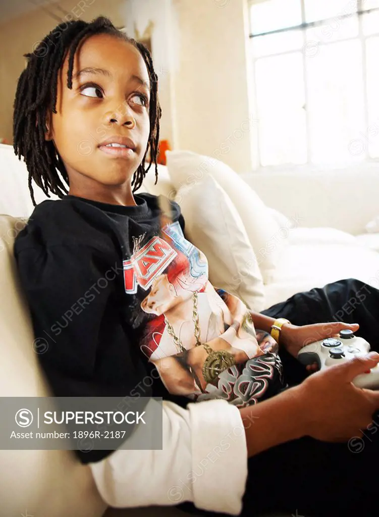 Boy sitting on couch playing TV game, Johannesburg, Gauteng, South Africa