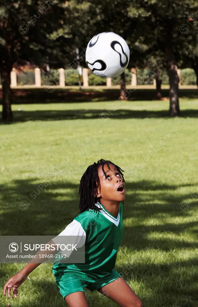 Boy in soccer outfit head butting ball, Zoolake Park, Johannesburg, Gauteng, South Africa
