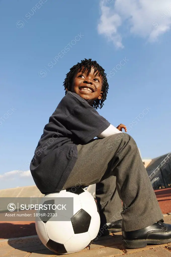 Young boy sitting on football, Super Stadium, Pretoria, Gauteng Province, South Africa