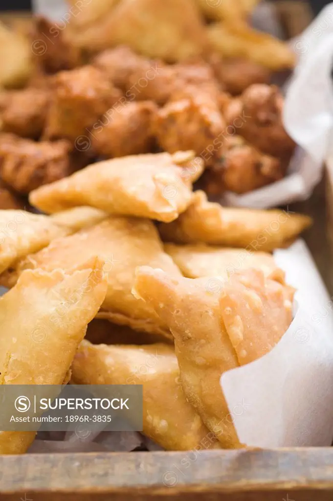 Close-up of Samosas on a Tray with Chilli Bites in the Background  Studio Shot