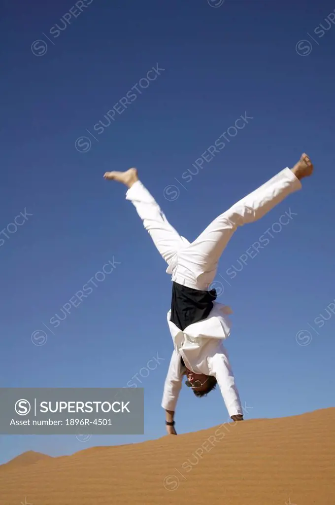 Man in a White Suit Doing a Handstand in the Desert  Namibia