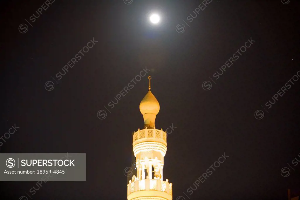 Minaret of Mosque Symmetrical with the Moon at Night  Dubai, United Arab Emirates