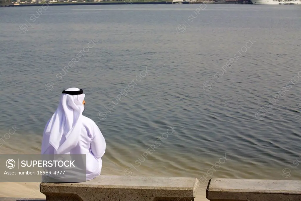 Arab Man Sitting in Park, Looking into Water  Dubai, United Arab Emirates