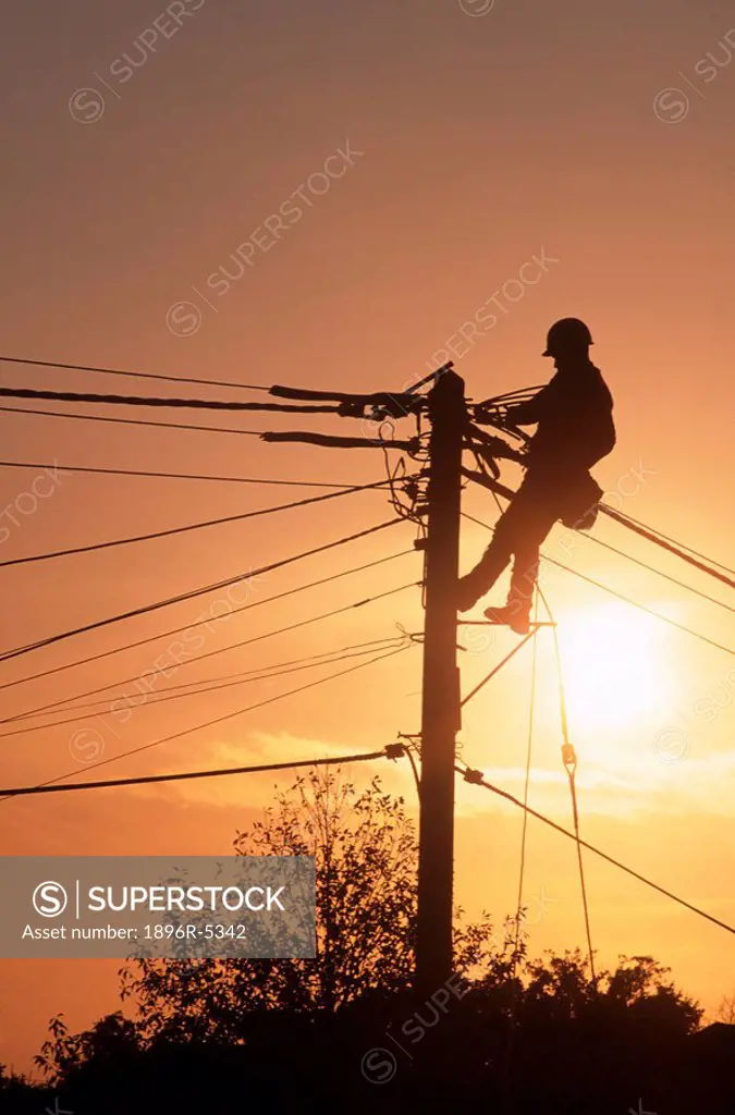 Silhouette of a Man Working on a Telegraph Pole at Sunset  England, United Kingdom