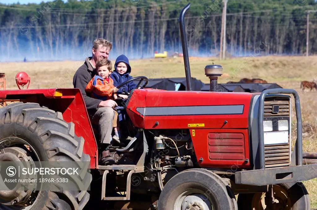 Father and Sons Sitting in Red Tractor  Luneburg, Northern KwaZulu Natal Province, South Africa