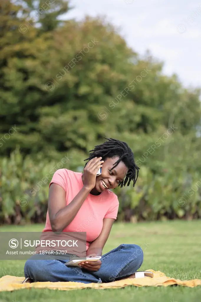Young Woman Sitting Cross Legged on the Grass Talking on her Cellphone  Grahamstown, Eastern Cape Province, South Africa