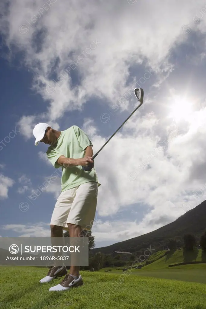 Low Angle View of Man Swinging Golf Club  Clovelly Golf Course, Cape Town, Western Province, South Africa