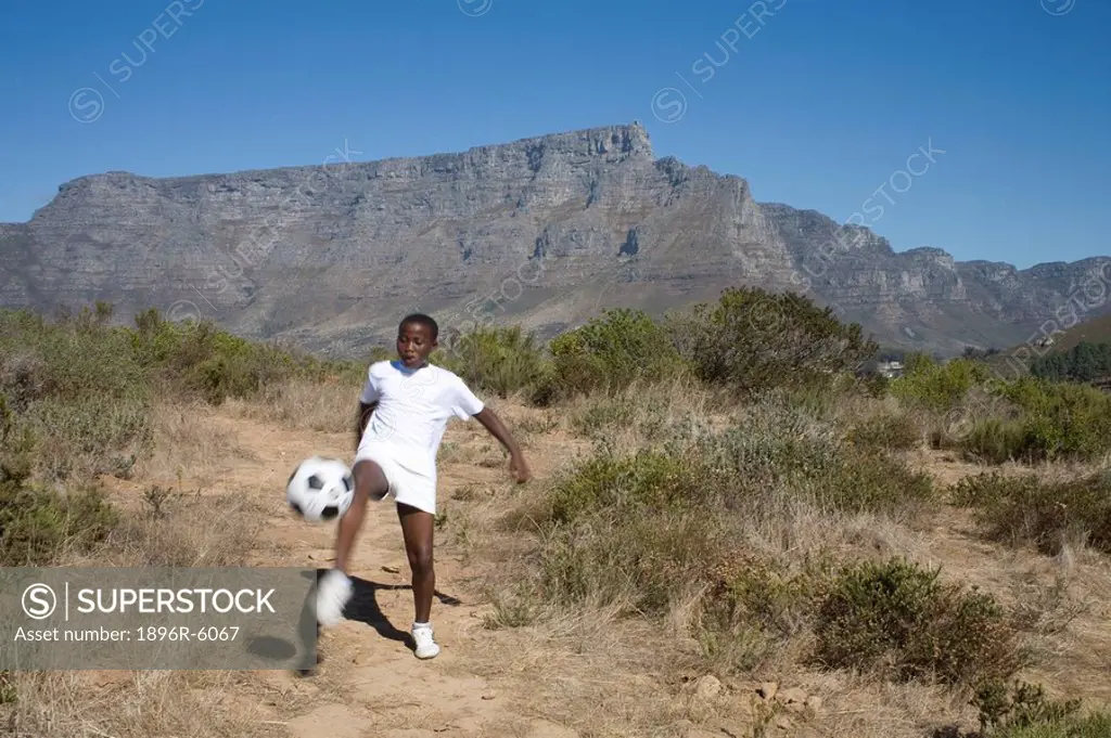 Boy bouncing football on his leg, Table Mountain in background, Cape Town, Western Cape Province, South Africa
